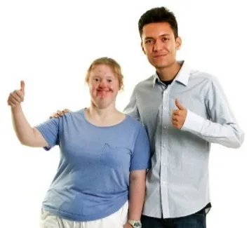 A woman with disability and a support worker are smiling with their thumbs up.