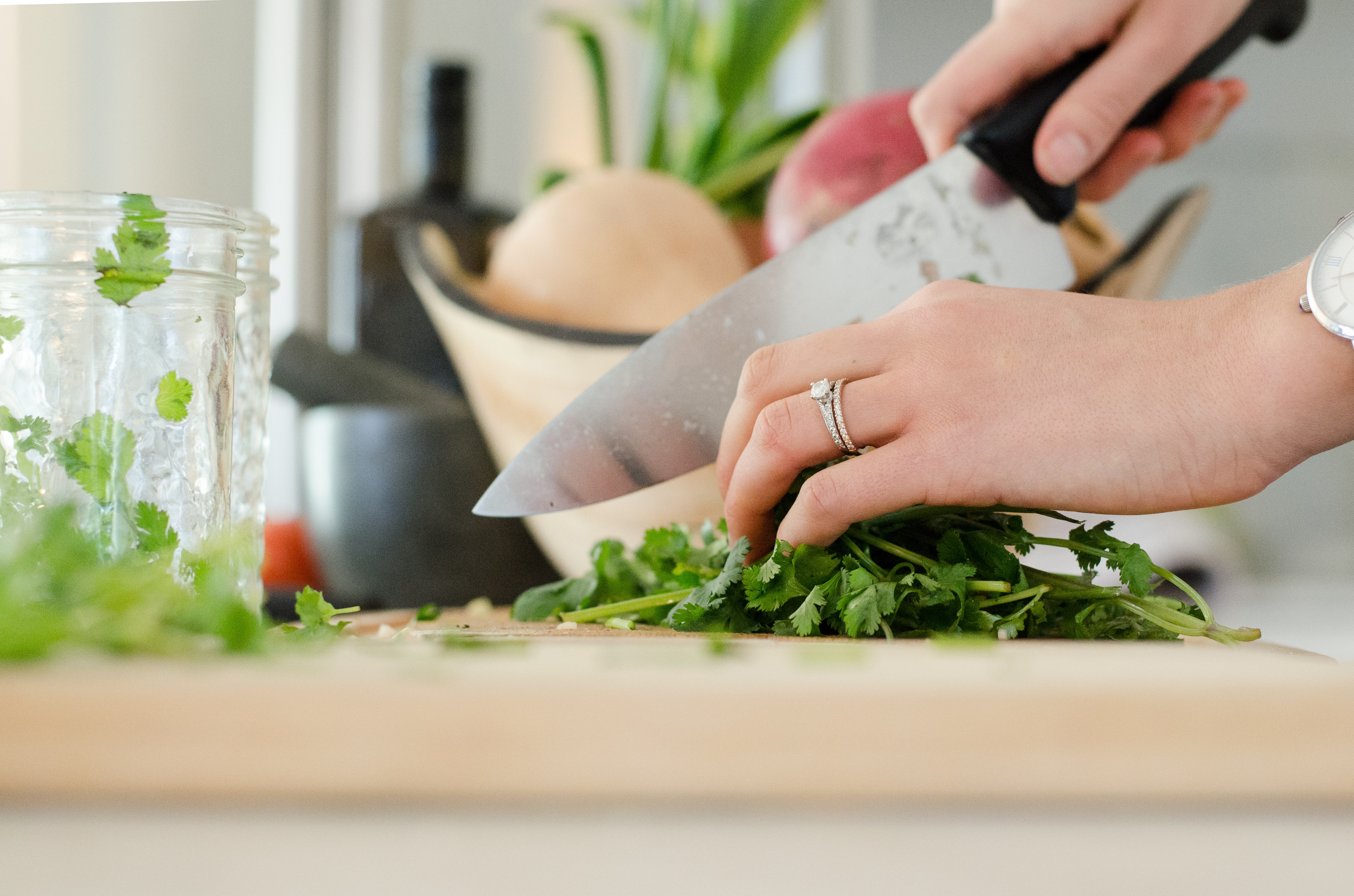 A close-up image of someone chopping green vegetables.