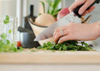 A close-up image of someone chopping green vegetables.