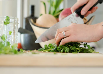 A close-up image of someone chopping green vegetables.