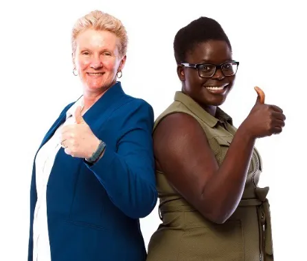Two women standing together with thumbs up.