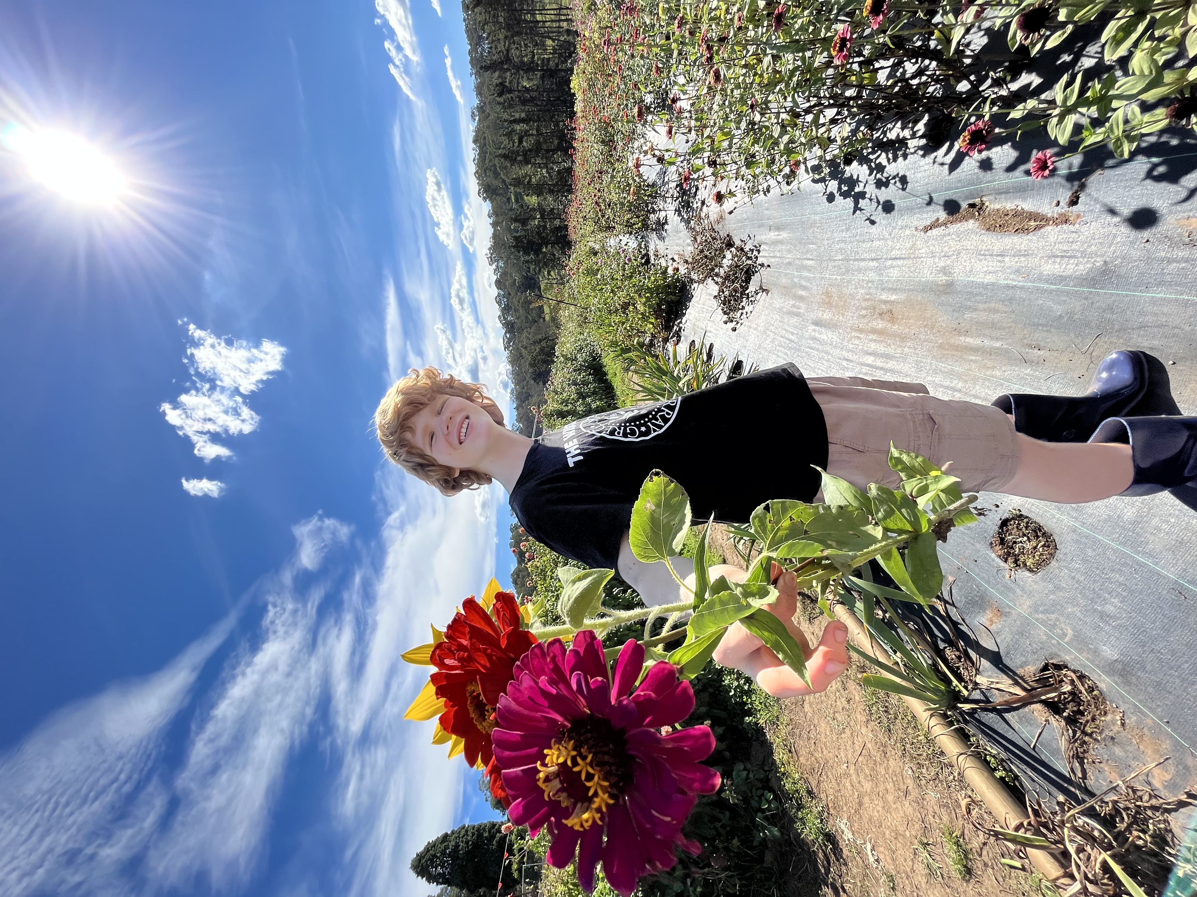 Image of author's son smiling and holding a bouquet of flowers toward the camera. It's a beautiful sunny day. 
