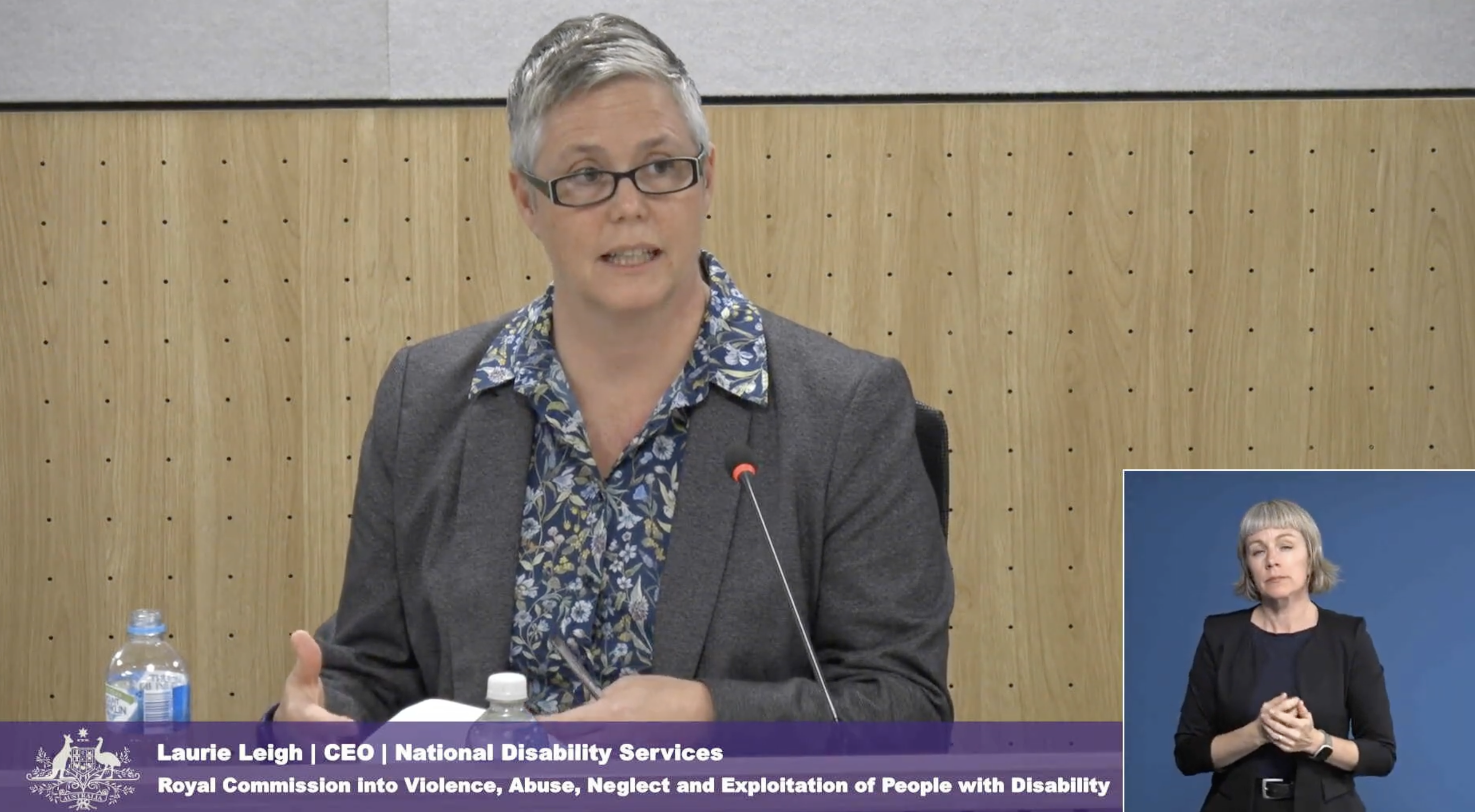 Image shows a screen shot of NDS CEO Laurie Leigh appearing at the Disability Royal Commission in February 2023. She is wearing a suit and glasses and is speaking into a microphone.
