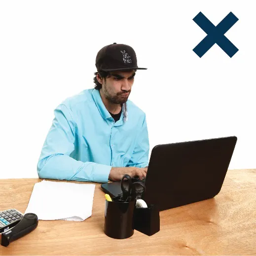 A man working on a lap top with a cross next to him.