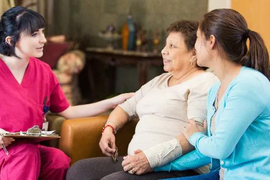 a mother and a daughter talking to a support worker, who has a clipboard