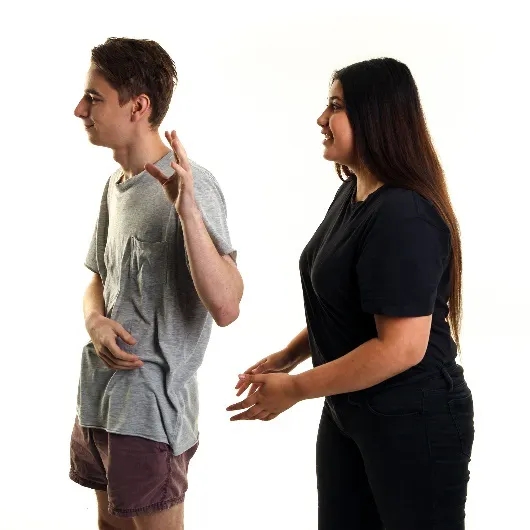 A woman trying to talk to a man but he has his back turned