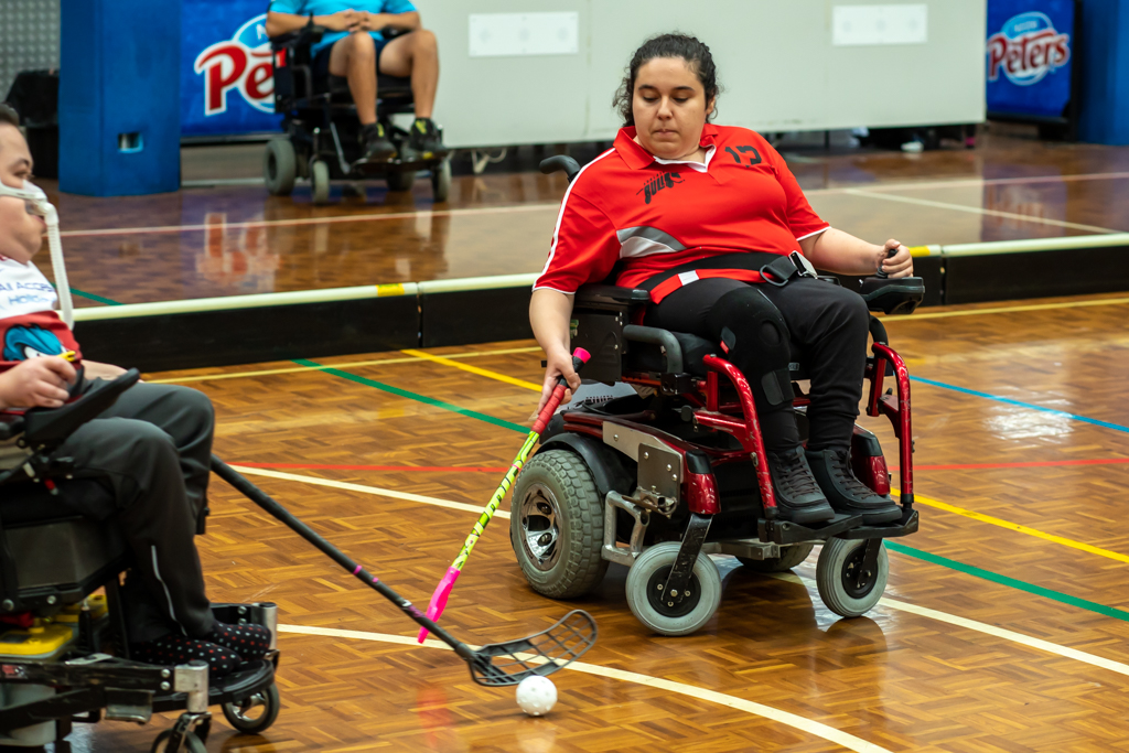 Chantel playing powerchair hockey on an indoor court. 
