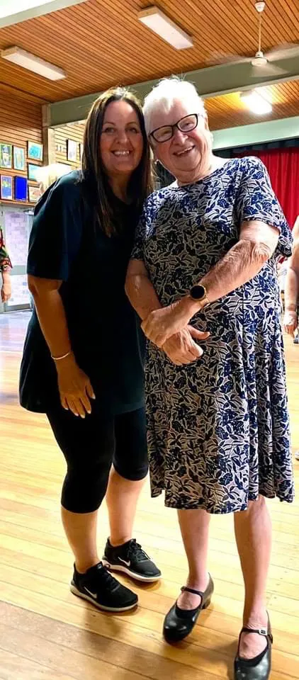 Noelene and Victoria and standing together at line dancing. Noelene is wearing glasses and has white hair. Both are smiling.