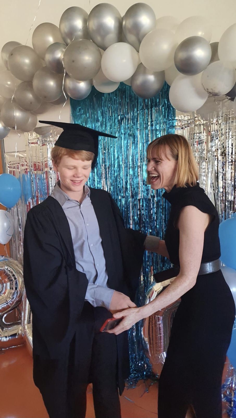 Author, Briana Blackett, with her son at his primary school graduation. Both are laughing.