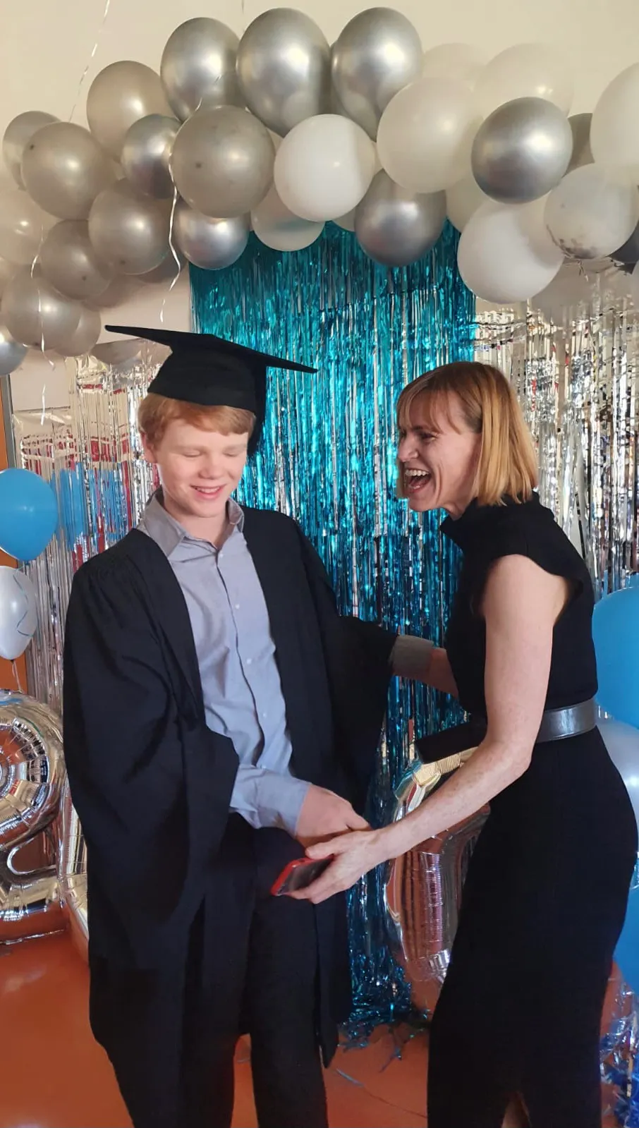 Briana Blackett at her son at his primary school graduation. Both are laughing.