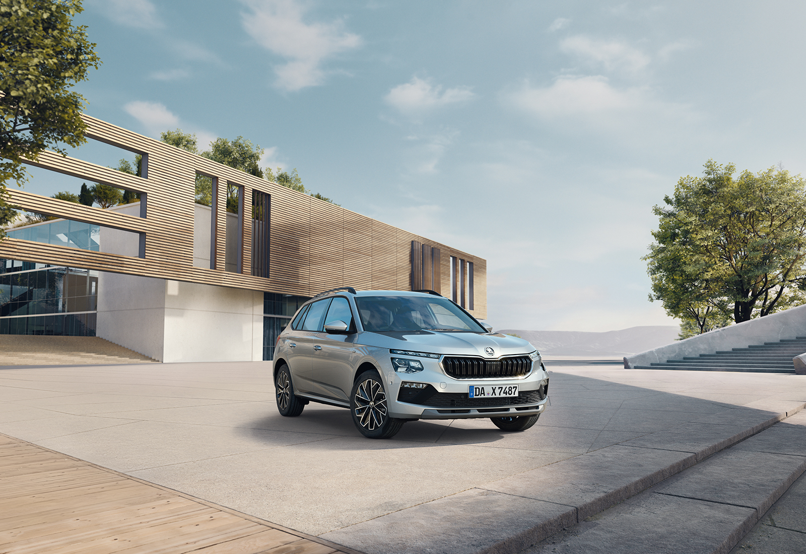 Silberner Škoda Kamiq vor einem modernen Gebäude geparkt