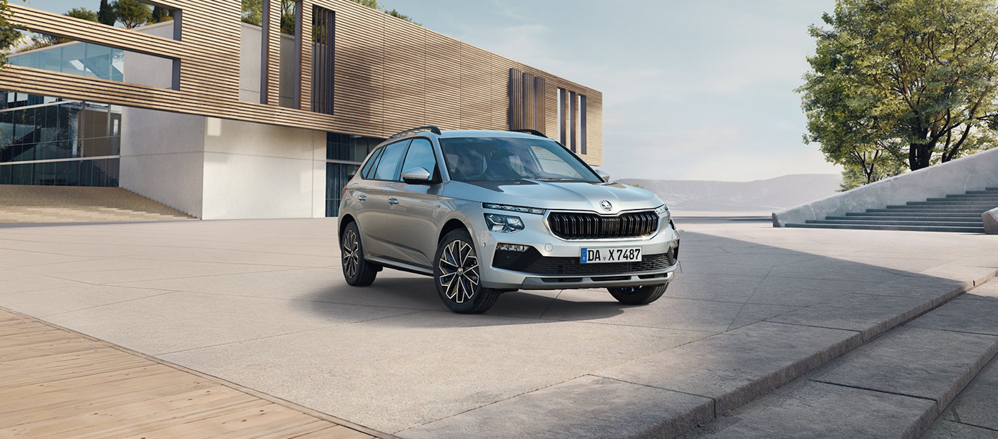 Silberner Škoda Kamiq vor einem modernen Gebäude geparkt