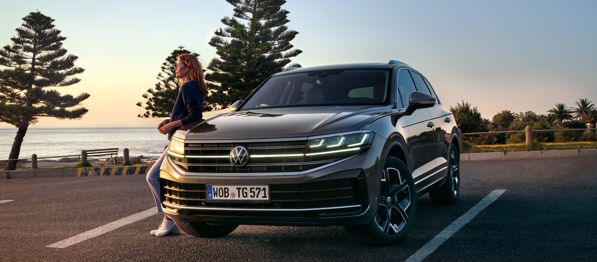 Frau lehnt an geparkten VW Touareg