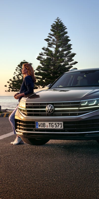 Frau lehnt an geparkten VW Touareg