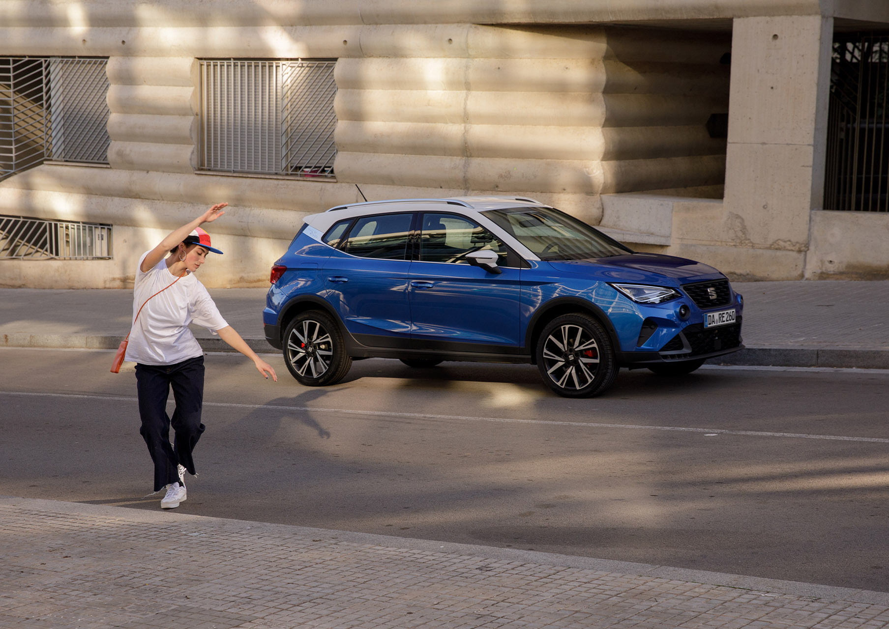 Person tanzt neben blauem SEAT Arona