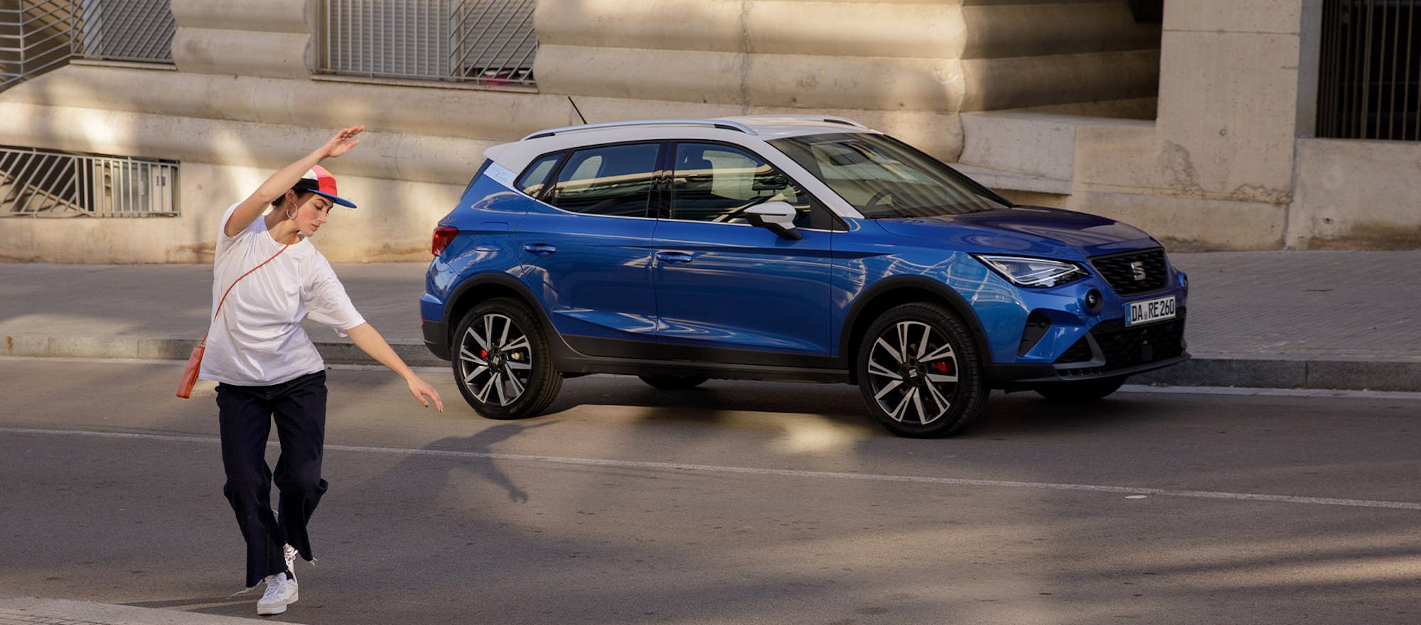 Person tanzt neben blauem SEAT Arona