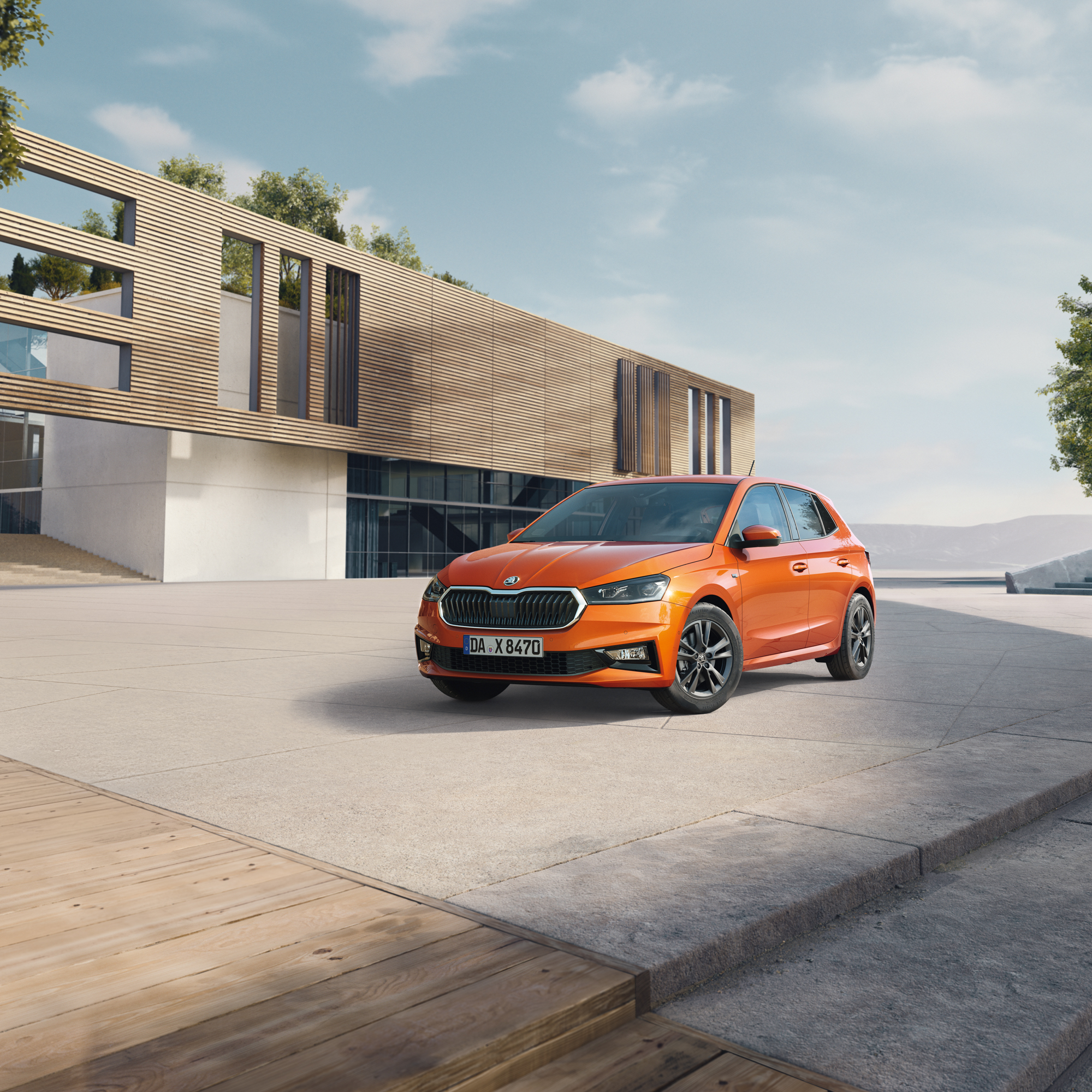 Orange farbener Skoda Fabia vor einem modernen Gebäude geparkt
