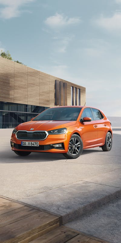 Orange farbener Skoda Fabia vor einem modernen Gebäude geparkt