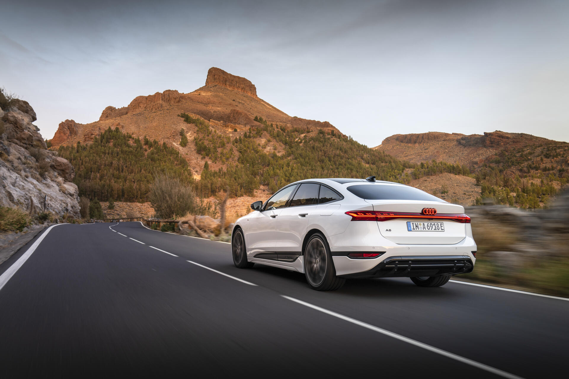 Audi A6 e-tron in Weiß bei Fahrt auf Bergstraße vor markanter Felslandschaft