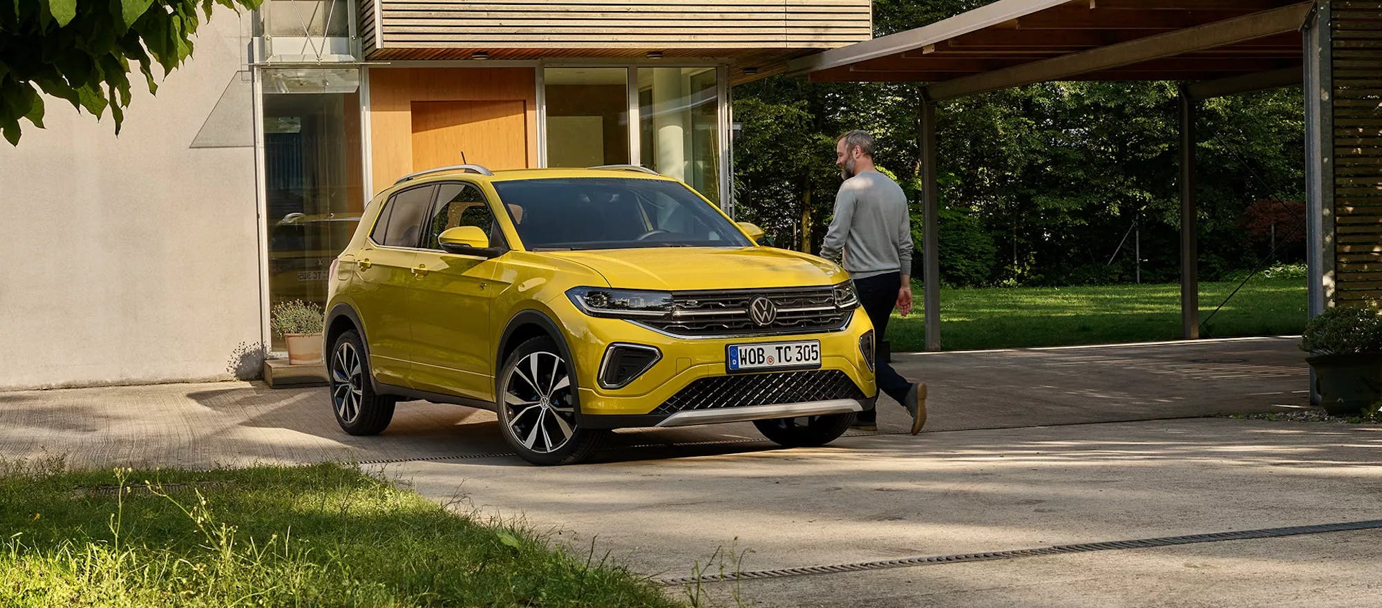 Gelber VW T-Cross, geparkt vor einem Gebäude mit einem Mann daneben