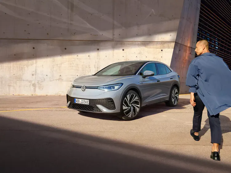 Mann läuft auf einen geparkten VW ID.5 zu