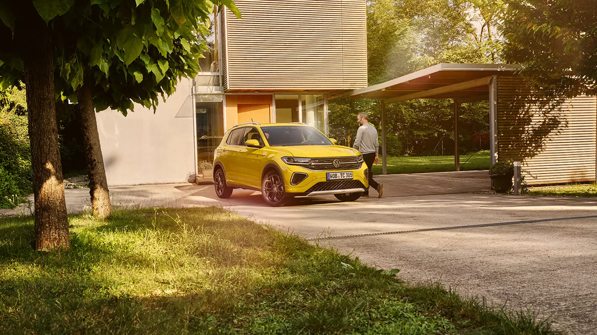 VW T-Cross in Gelb vor einem modernen Einfamilienhaus mit Carport