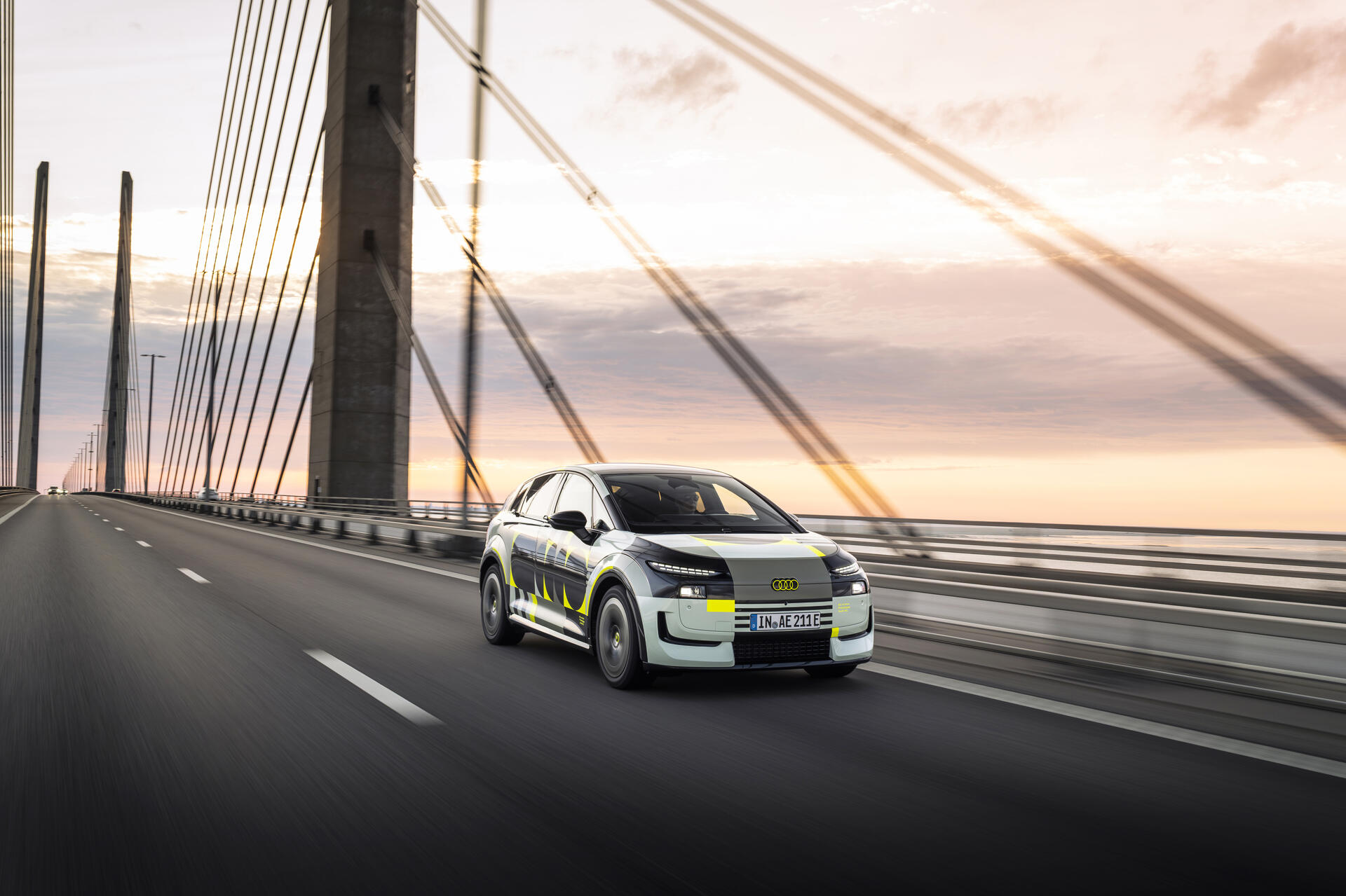 Audi A2 e-tron Prototyp mit Tarnfolierung bei Testfahrt auf Brücke bei Sonnenuntergang, Dreiviertelfrontansicht