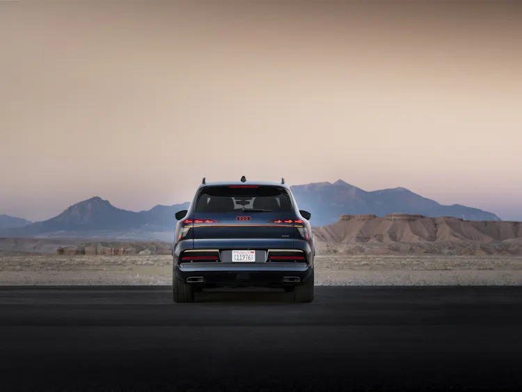 Audi Q9 in Dunkelblau, Heckansicht stehend vor Bergpanorama in der Abenddämmerung