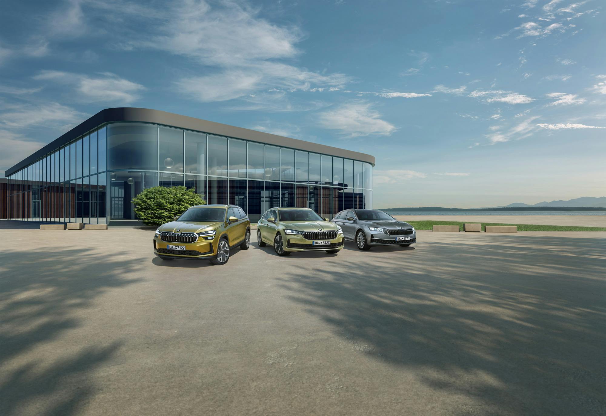 Drei nebeneinander geparkte Skoda Fahrzeguge vor einem großen gläsernen Gebäude