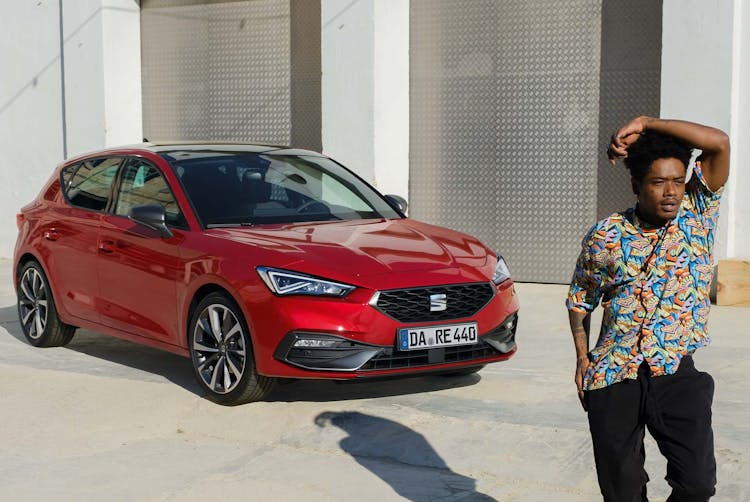 Mann steht vor geparktem SEAT Leon