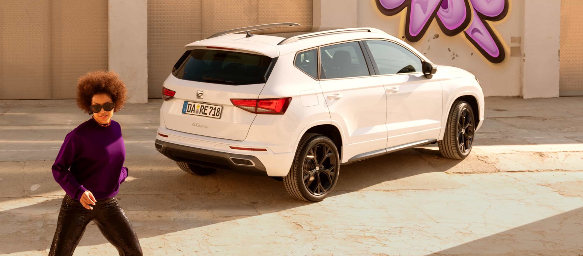 Frau geht neben geparktem SEAT Ateca
