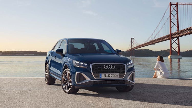 Dunkelblauer Audi Q2 vor Wasser und Brücke geparkt