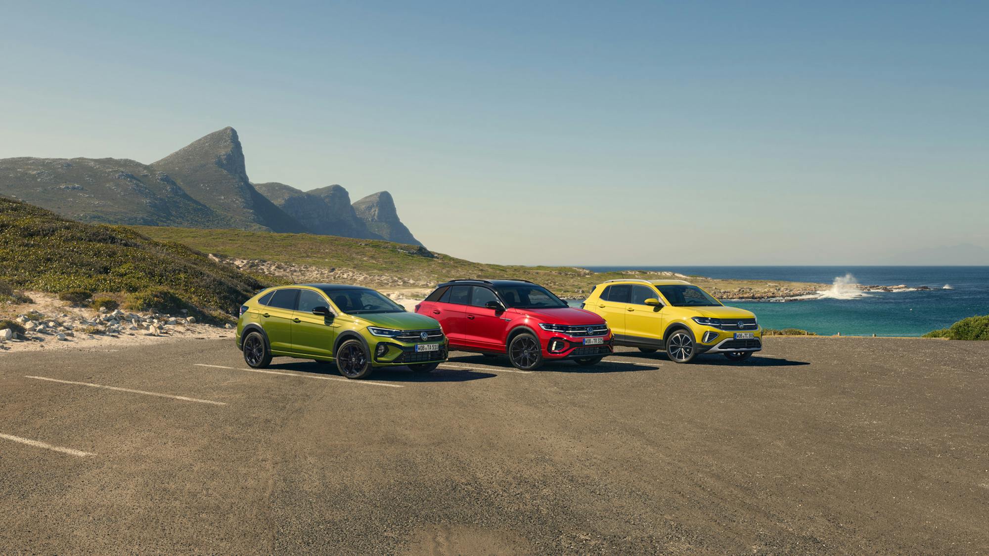 Drei Fahrzeuge von VW nebeneinander geparkt in sommerlicher Kulisse am Meer