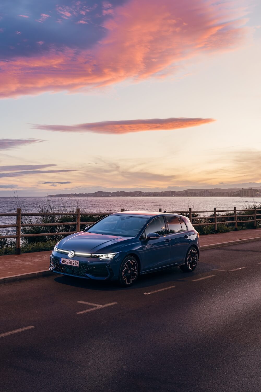 VW Golf auf der Straße mit Meer im Hintergrund bei Sonnenuntergang