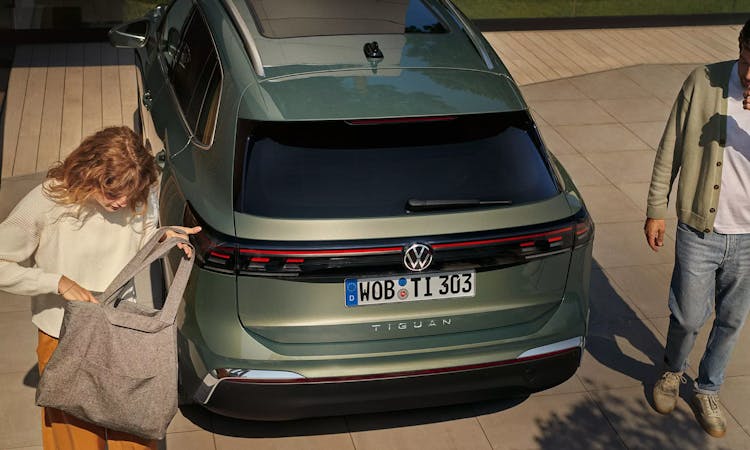 Heckansicht des VW Tiguan mit zwei Personen daneben