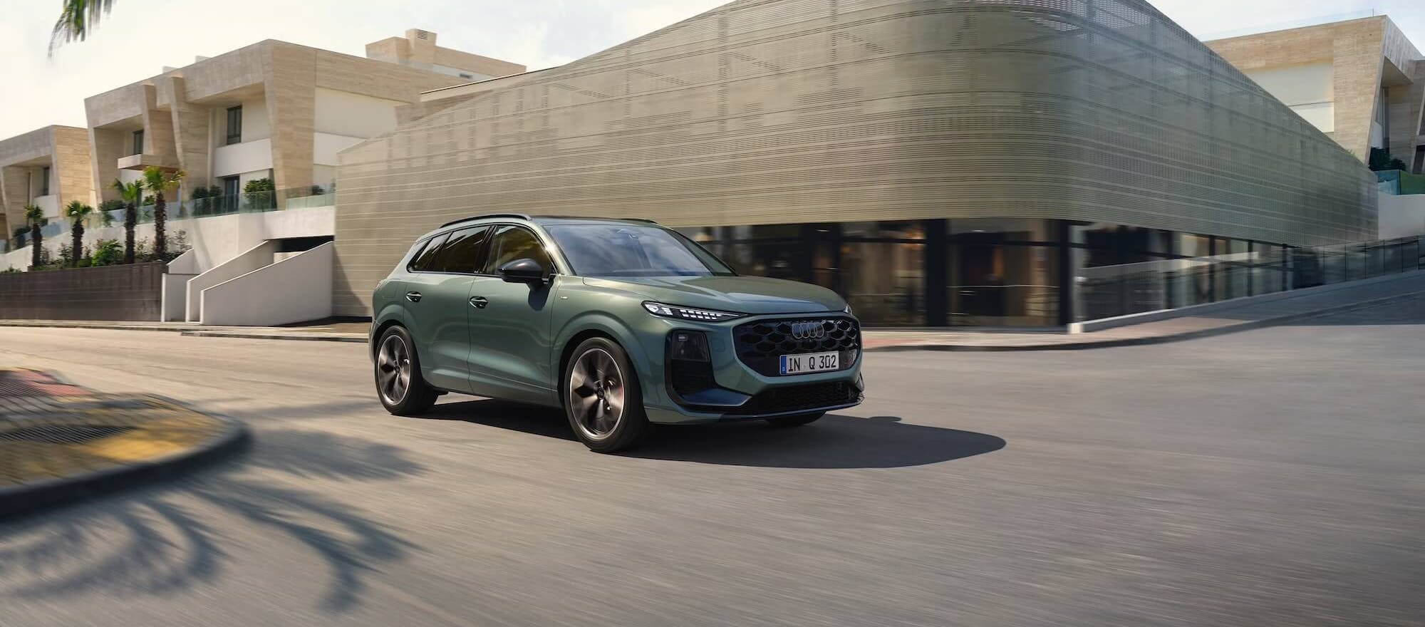 Audi Q3 fährt in urbaner Umgebung vor einem modernen Gebäude