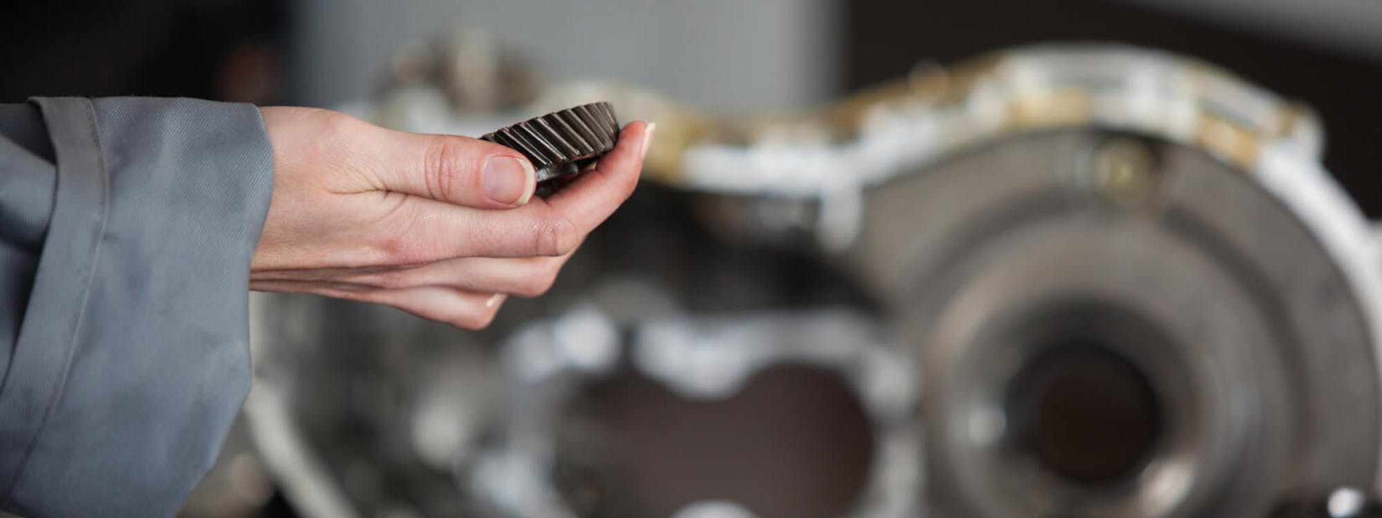 Zahnriemen, der in einer Hand neben einem Motor gehalten wird