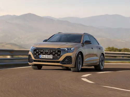 Frontansicht eines fahrenden Audi Q8 mit Bergen im Hintergrund