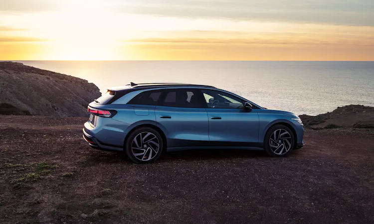 Geparkter VW ID7 Tourer am Meer bei Sonnenuntergang