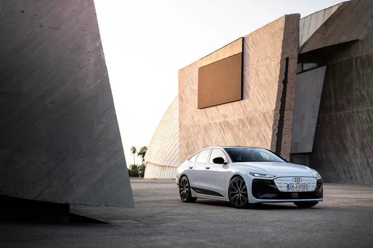 Audi A6 e-tron in Weiß, Dreiviertelfrontansicht vor markanter Betonarchitektur