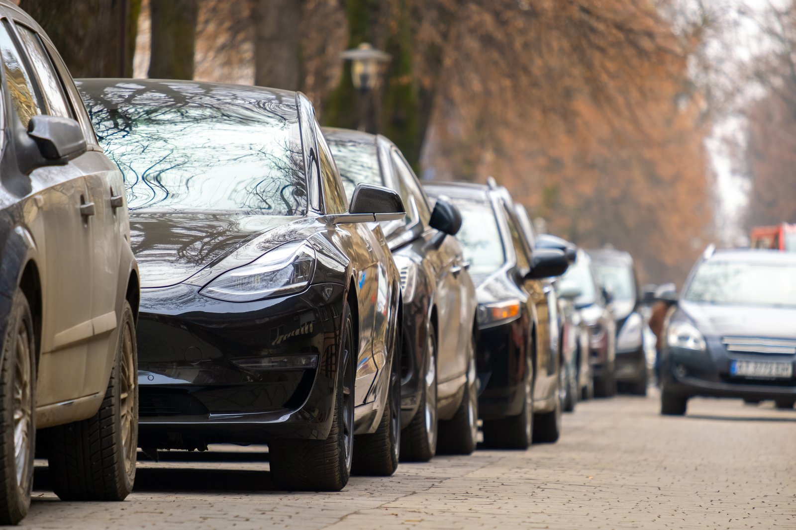 Reihe parkender Autos mit unterschiedlichen Antrieben am Straßenrand 