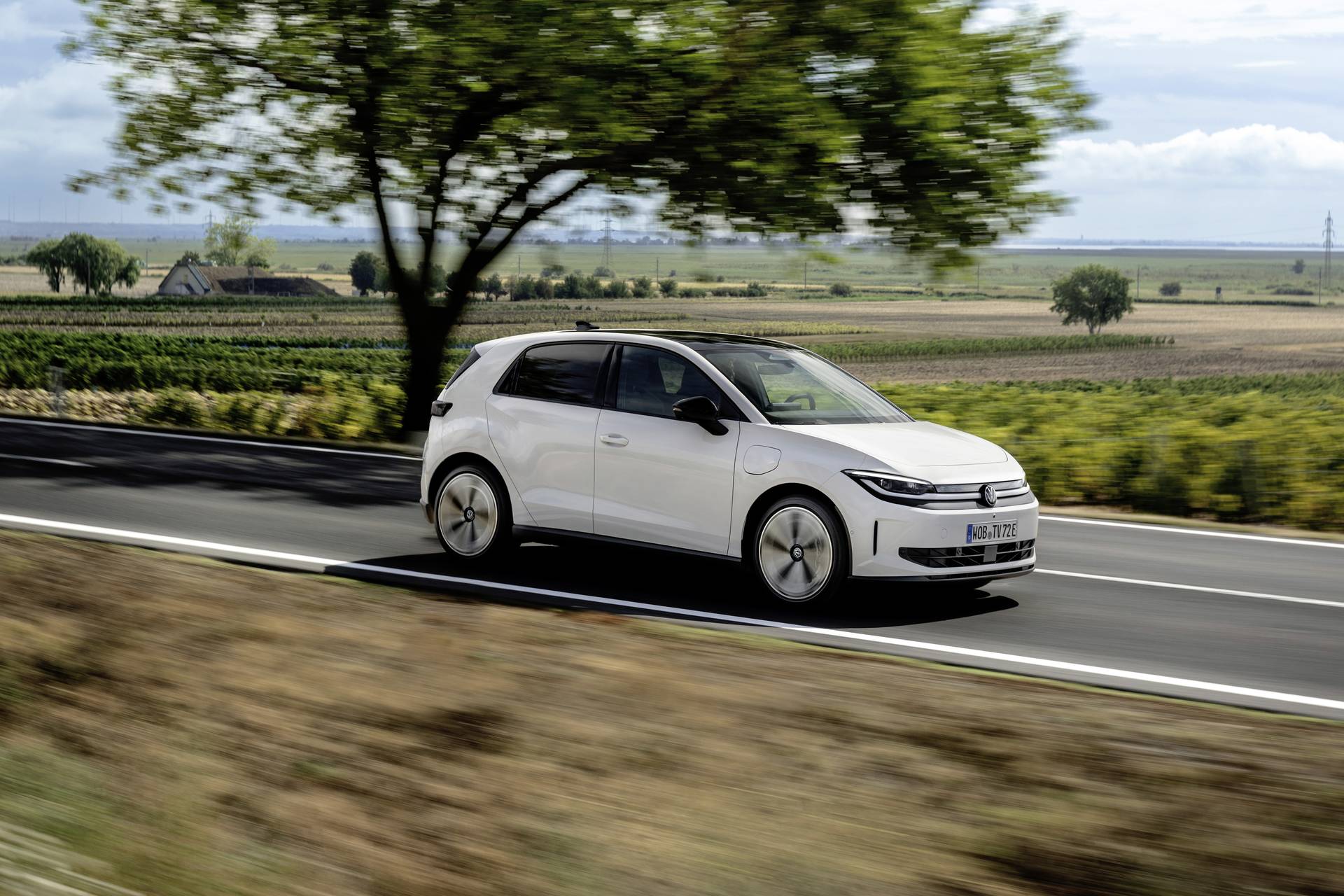 VW ID. Polo in Weiß, Seitenansicht in Fahrt auf einer Landstraße bei Sonnenschein