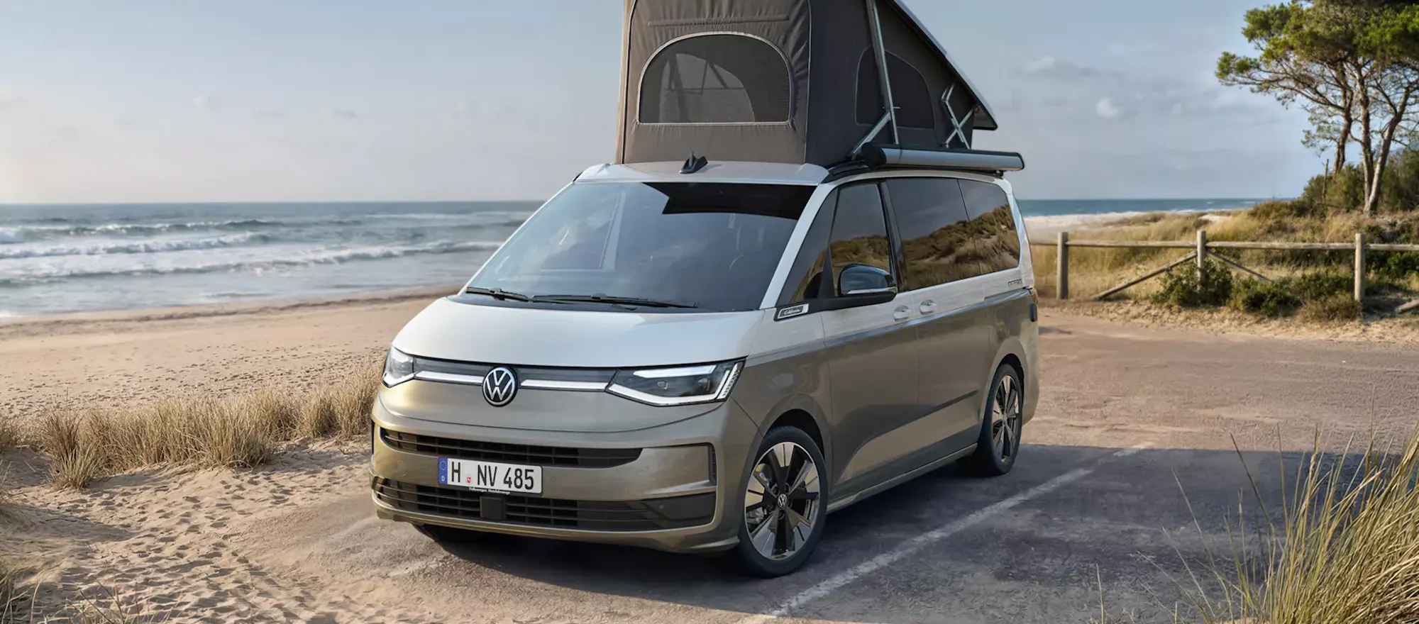 VW California mit ausgeklapptem Aufstelldach an einem Strand geparkt