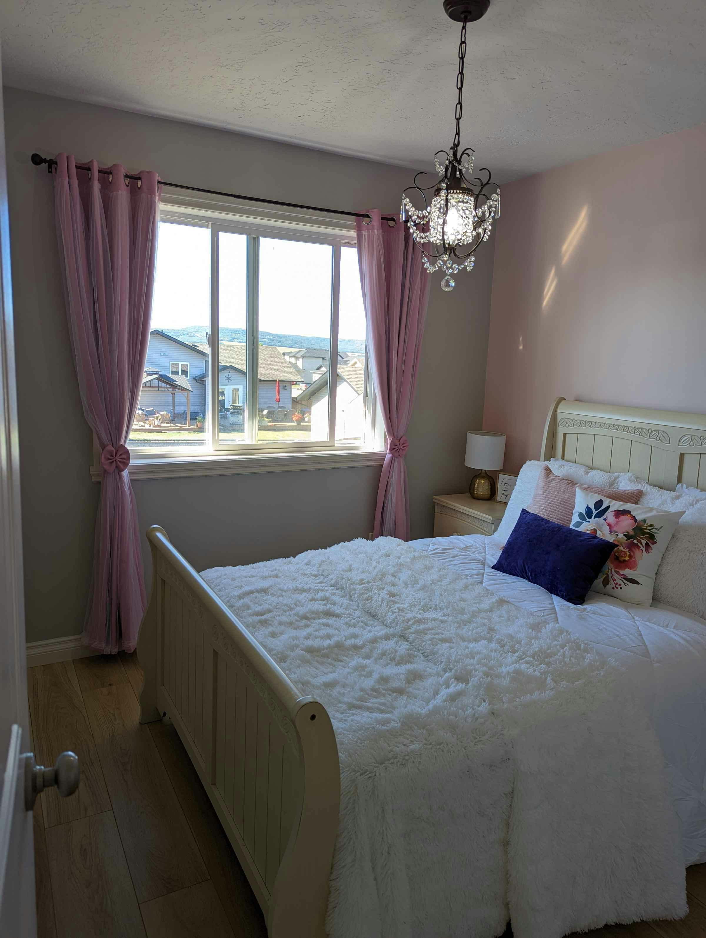 Bedroom with chic chandelier light and pink curtains