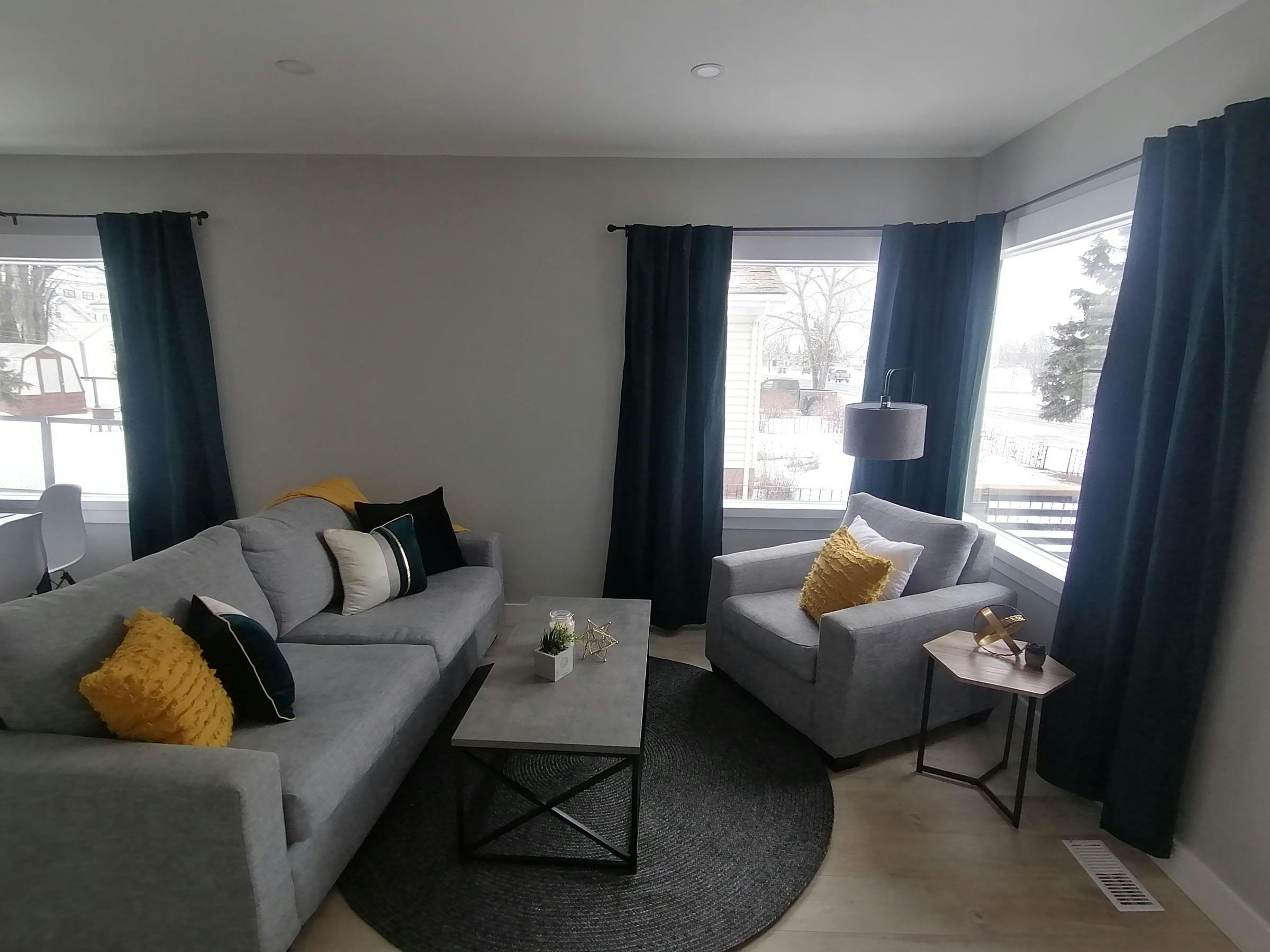 Staged living room with gray couch and chair and navy blue curtains