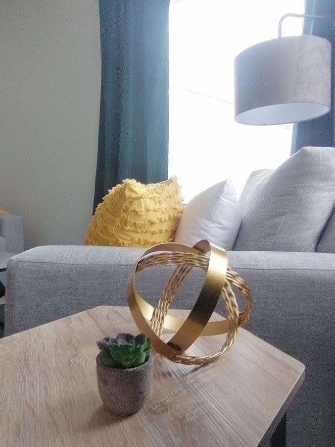 Gray couch with throw pillows and wooden side table