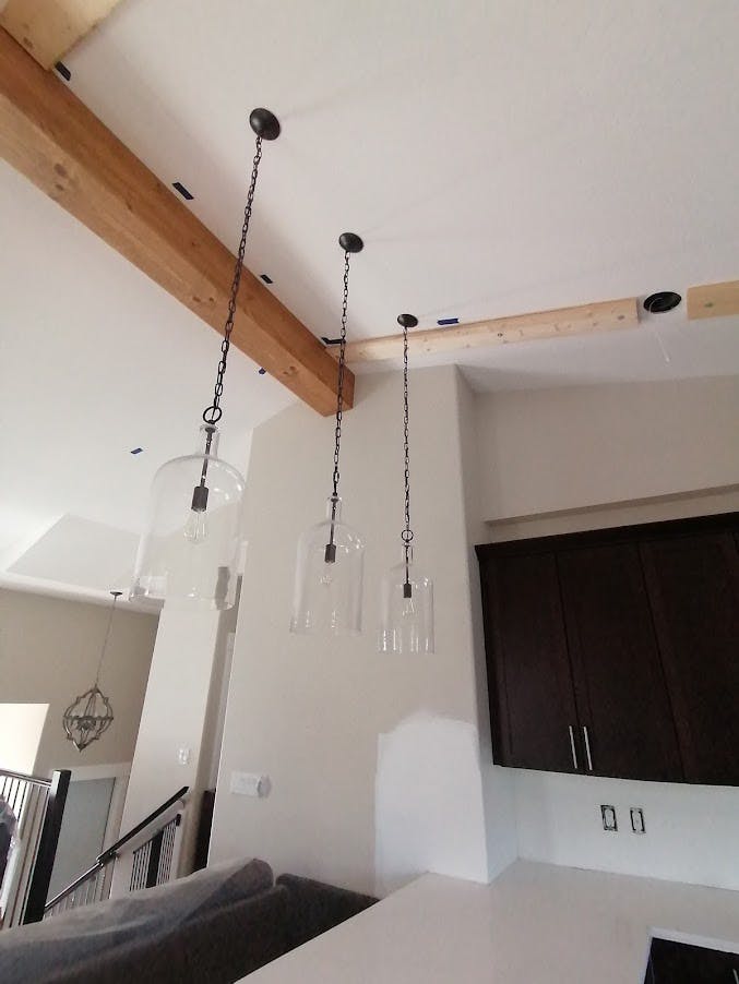 Wood accent beams and chic lighting in kitchen