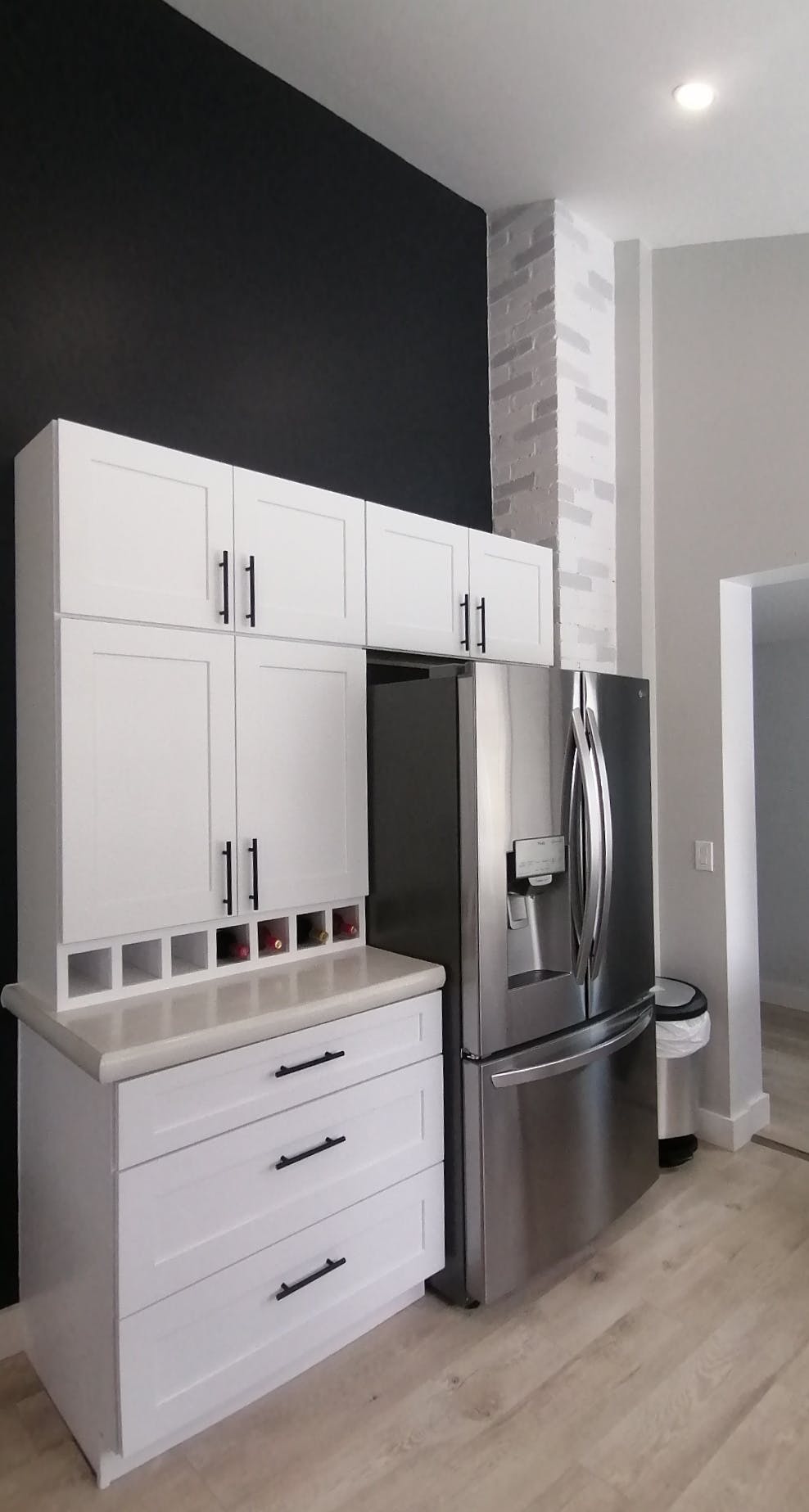 Stainless fridge with white cupboards built around it