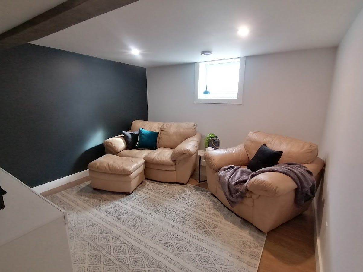 Staged basement room with blush brown couches and dark throw pillows