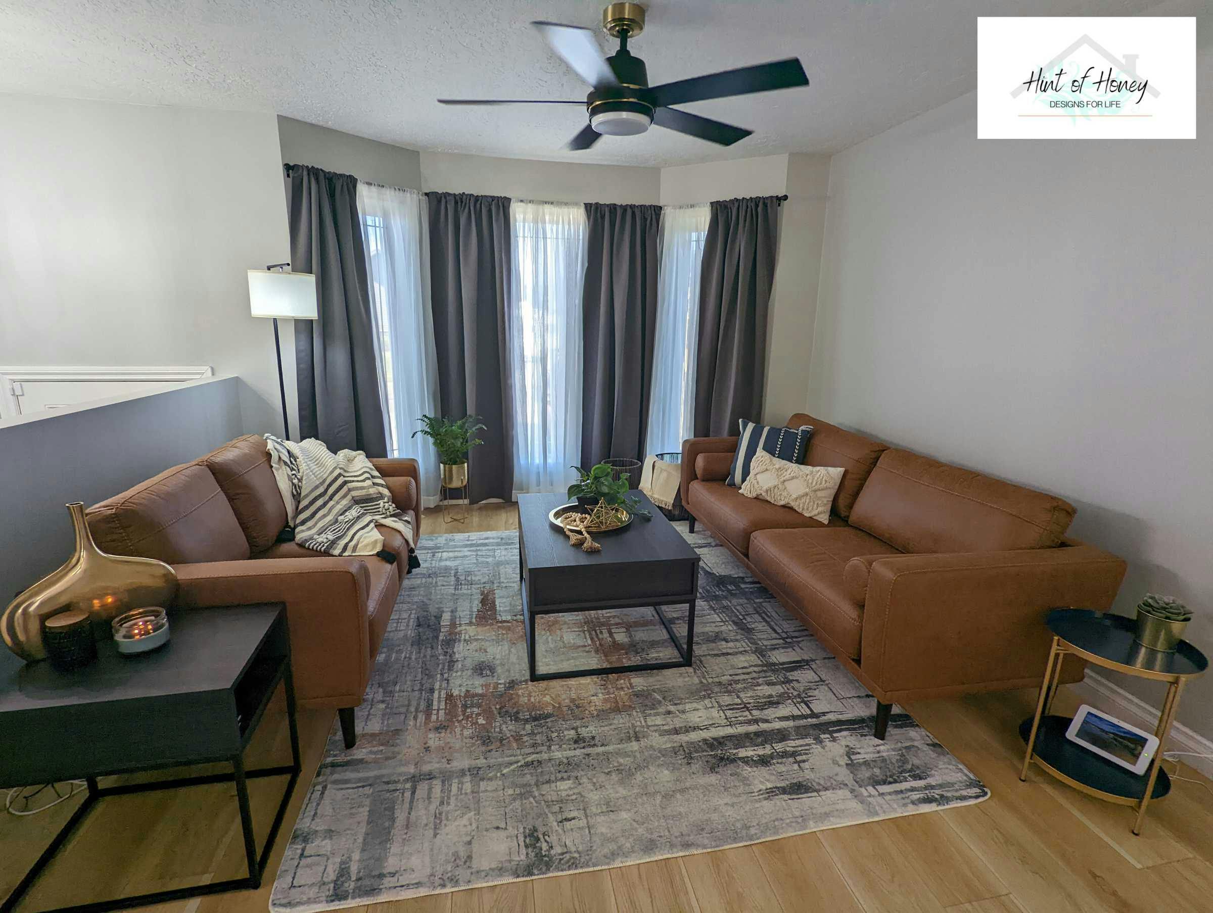 Staged modern looking living room with leather couches and modern looking fan